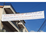 A banner hanging across a building, honoring the achievements of Mayassa Bou-Dargham in her Lebanese hometown